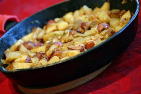 Cast iron skillet with crispy potatoes inside.
