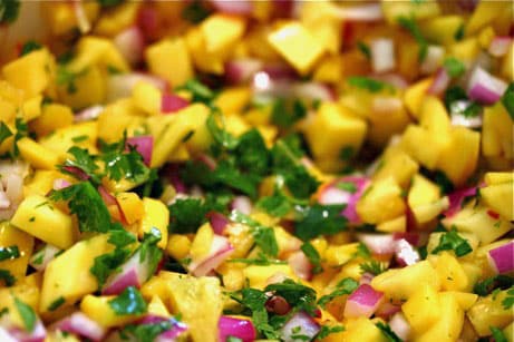 A bowl of mango salsa with cilantro.