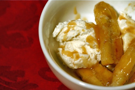 Ice cream in a bowl with sauteed bananas and sauce.
