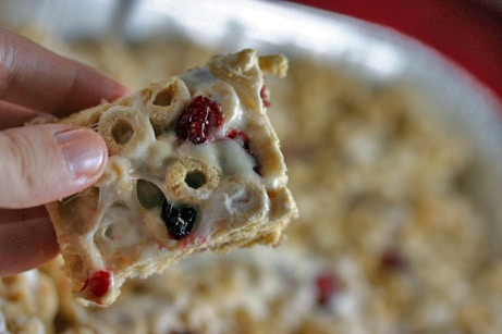 Holding a square cereal bar with dried cranberries.