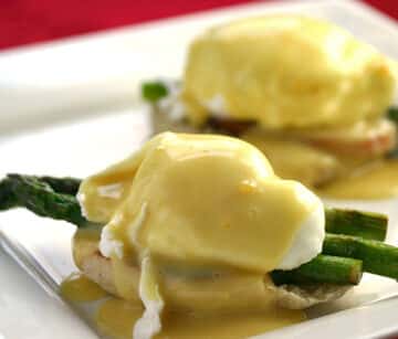 Eggs benedict with asparagus on a plate.