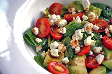 Bowl of salad with tomatoes and cheese.