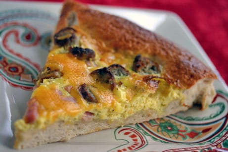 Slice of breakfast pizza on a plate.