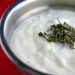 Bowl of yogurt sauce topped with dried mint.