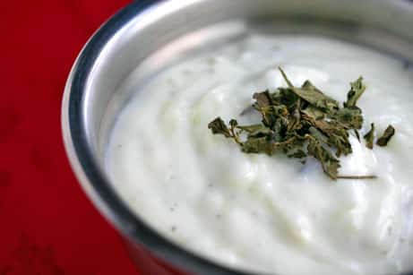 Bowl of yogurt sauce topped with dried mint.