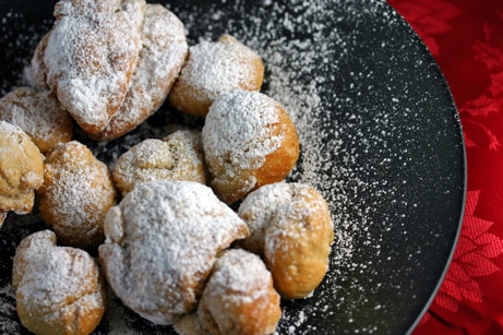 Pile of fried zeppole dusted with powdered sugar.