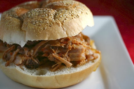 Pulled pork sandwich on a sesame seed bun.