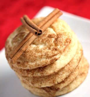 Stack of snickerdoodle cookies topped with cinnamon sticks.