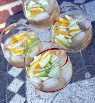 Glasses of white sangria with fruit on a table.