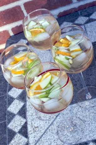 Glasses of white sangria with fruit on a table.