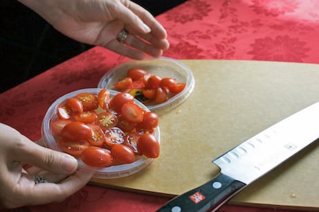 Slicing tomatoes using plastic lids as a guide.