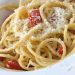 A bowl of pasta with tomatoes and Parmesan.