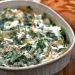 Spinach dip with caramelized onions in a casserole dish.