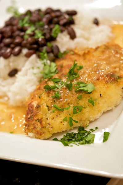 Plate of crusted chicken with beans and rice.