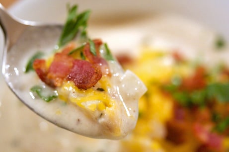 Spoonful of baked potato soup with bacon.