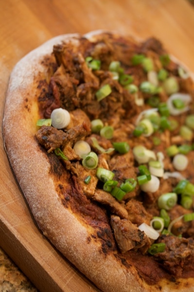 Jerk chicken pizza on a cutting board.