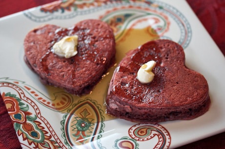 Heart-shaped red velvet pancakes on a plate.