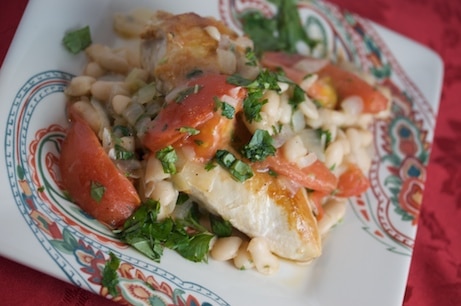 Chicken with warm bean salad on a plate.