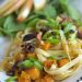 A plate of pasta with squash and bacon.