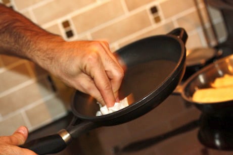 A person spreading oil in a skillet with a paper towel.