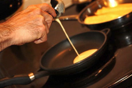 Pouring crepe batter into a small skillet.