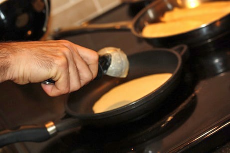 Pouring crepe batter into a skillet.