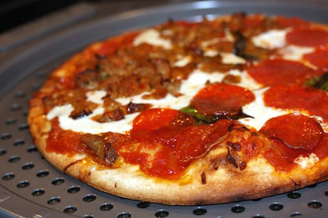 Pepperoni and meatball pizza on a baking sheet.