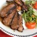 A plate of sliced steak and salad.