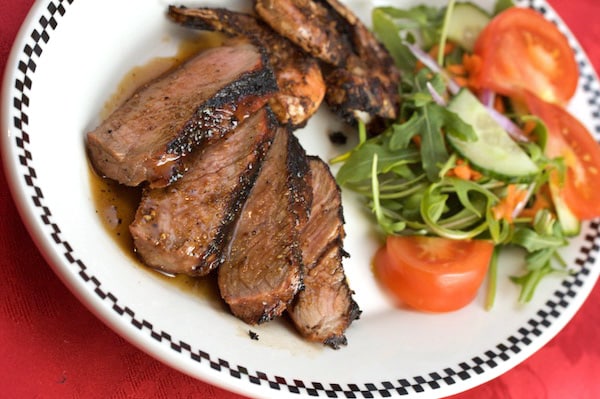 A plate of sliced steak and salad.