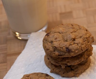 A stack of chocolate cookies with a glass of milk.