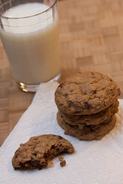 A stack of chocolate cookies with a glass of milk.