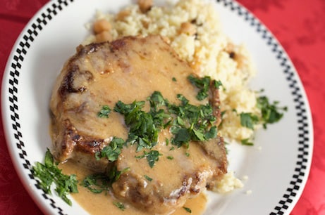 A plate of smothered pork chops with couscous.