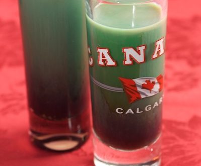 Double shot glasses with green cocktail inside.