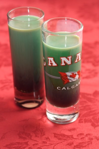 Double shot glasses with green cocktail inside.