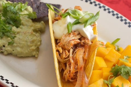 Chicken taco with guacamole and tortila chips.