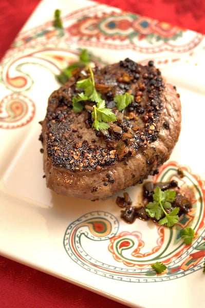 Peppercorn-crusted steak on a plate.