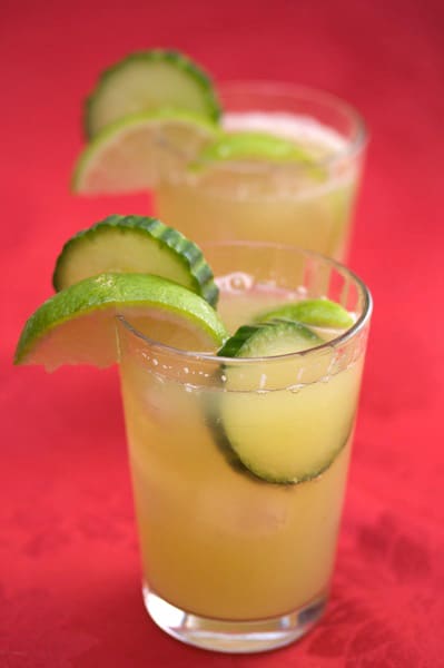 Two glasses of agua fresca with cucumber and lime garnishes.