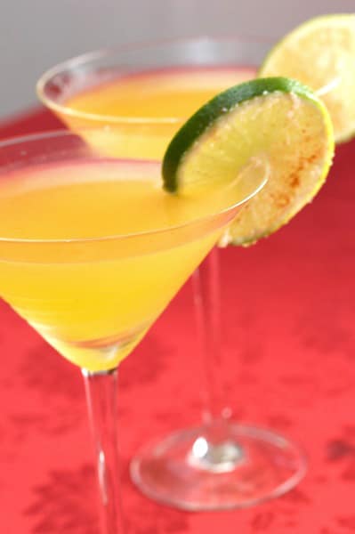 Two passion fruit chili margaritas with lime wheel garnish.