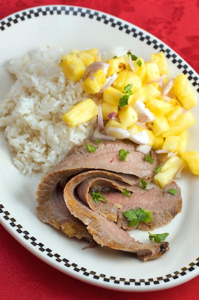 A plate of sliced flank steak with pineapple salsa and rice.