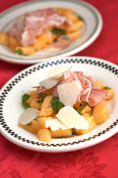 Cantaloupe and prosciutto on a plate with shaved Parmesan.