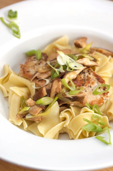 A plate of egg noodles with a turkey cutlet on top.