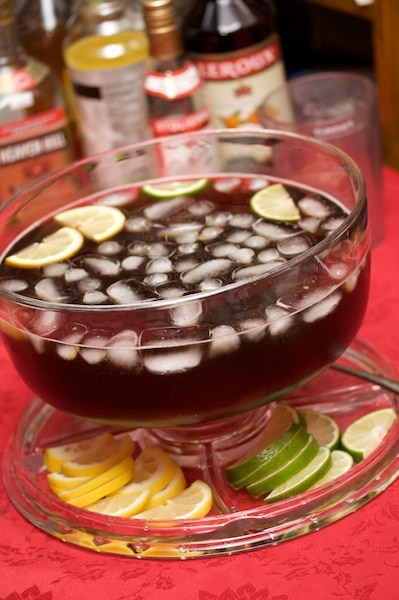 Punch bowl full of Texas tea with lemon and lime wedges.