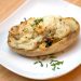 Twice baked potato on a plate with chives.