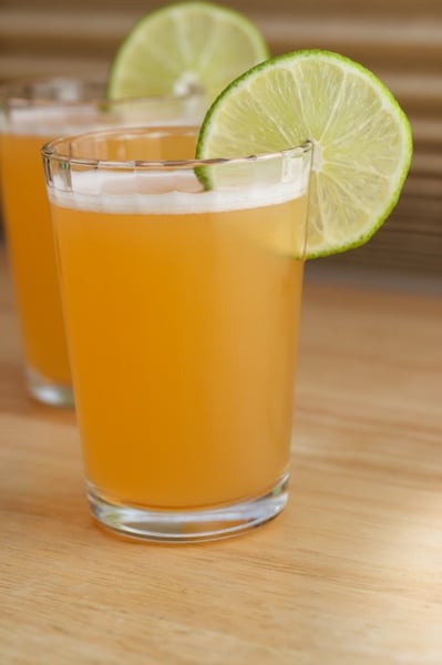 Two glasses of melon juice with lime wheel garnish.