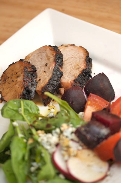 Sliced pork tenderloin with a salad alongside.