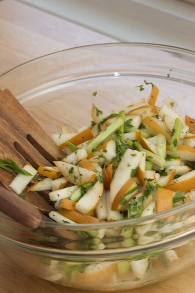 Bowl of Asian pear slaw with serving utensils.