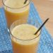 Two glasses of orange, apple, & celery juice with straws.
