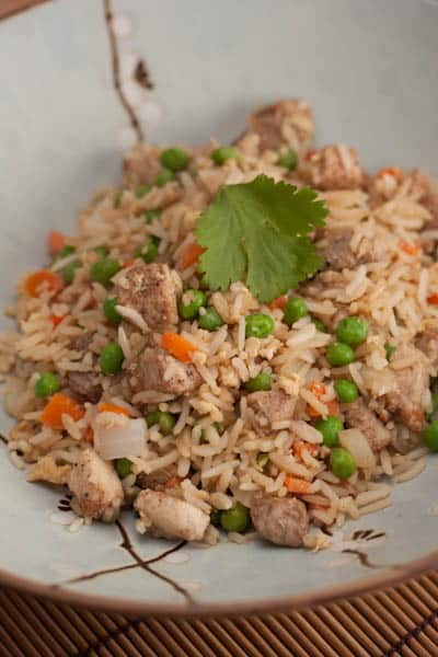 A bowl of pork fried rice and vegetables.