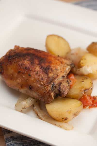 A plate of baked chicken with potatoes.