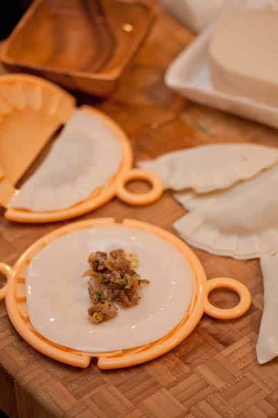 Assembling Jamaican beef dumplings with a dumpling press.